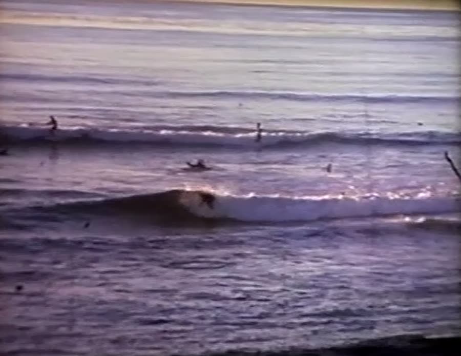 A surfer riding a small wave in golden evening light